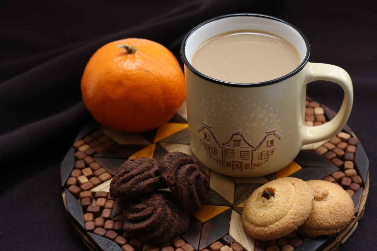 White ceramic mug beside orange and cookies