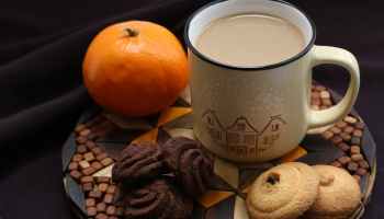 White ceramic mug beside orange and cookies